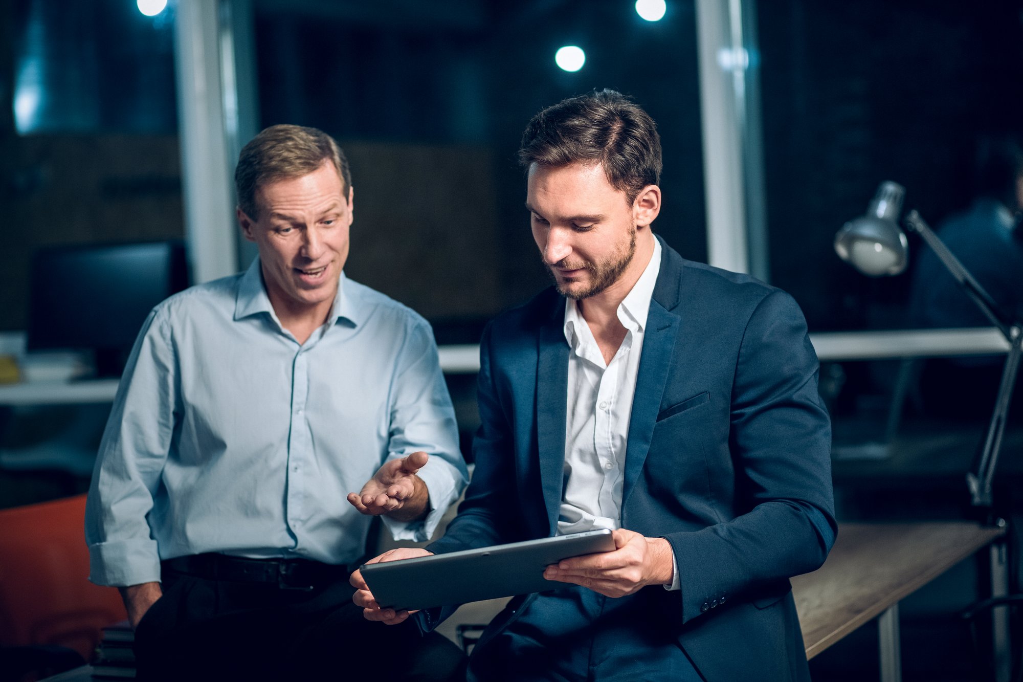 two-office-workers-with-tablet-office-late-night-young-businessmen-talking-while-viewing-presentation-digital-touchscreen-tablet two-office-workers-with-tablet-office-late-night-young-businessmen-talking-while-viewing-presentation-digital-touchscreen-tablet